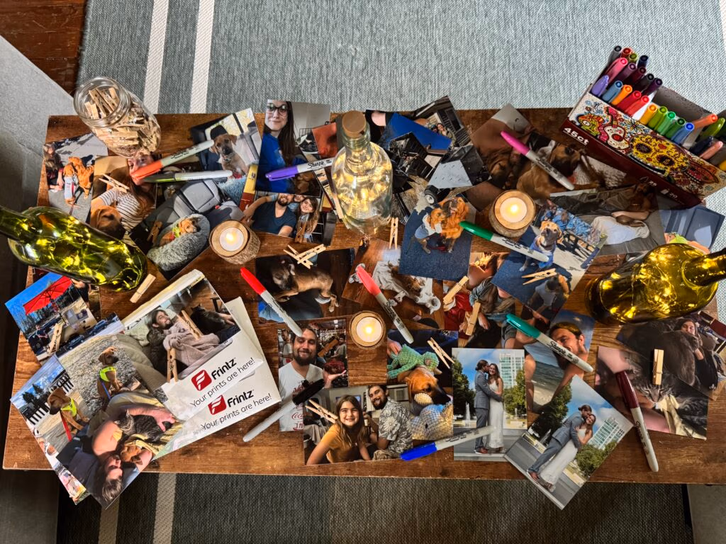 DIY birthday party photo craft station with printed 4x6 photos, markers, clothespins, and candles on a wooden table