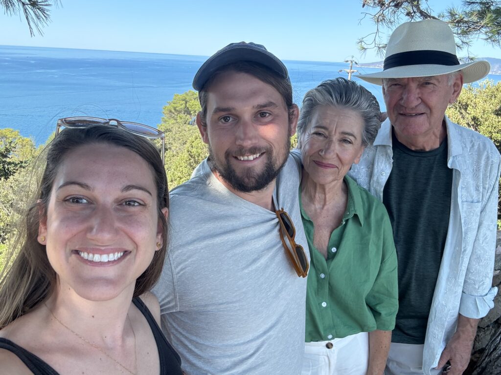 A smiling family, selfie-style, with the sea in the background.